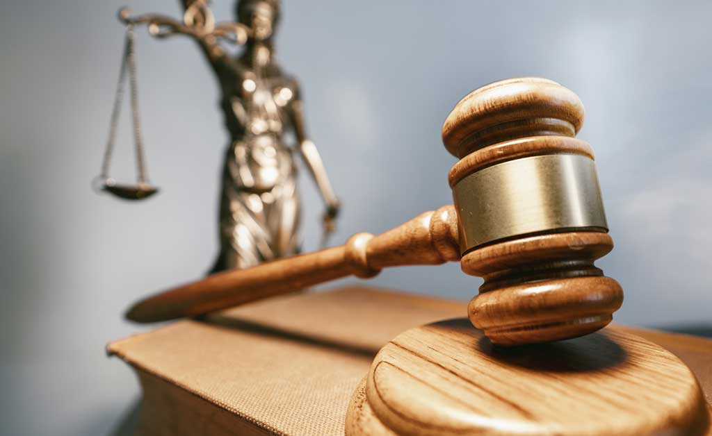 A wooden gavel and block with a golden justice lady in the background representing how one can benefit from calling a Portland criminal defense attorney.