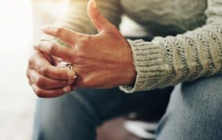 Common Mistakes to Avoid During Maine Divorce portrayed by a man hold his wedding ring in his hand.
